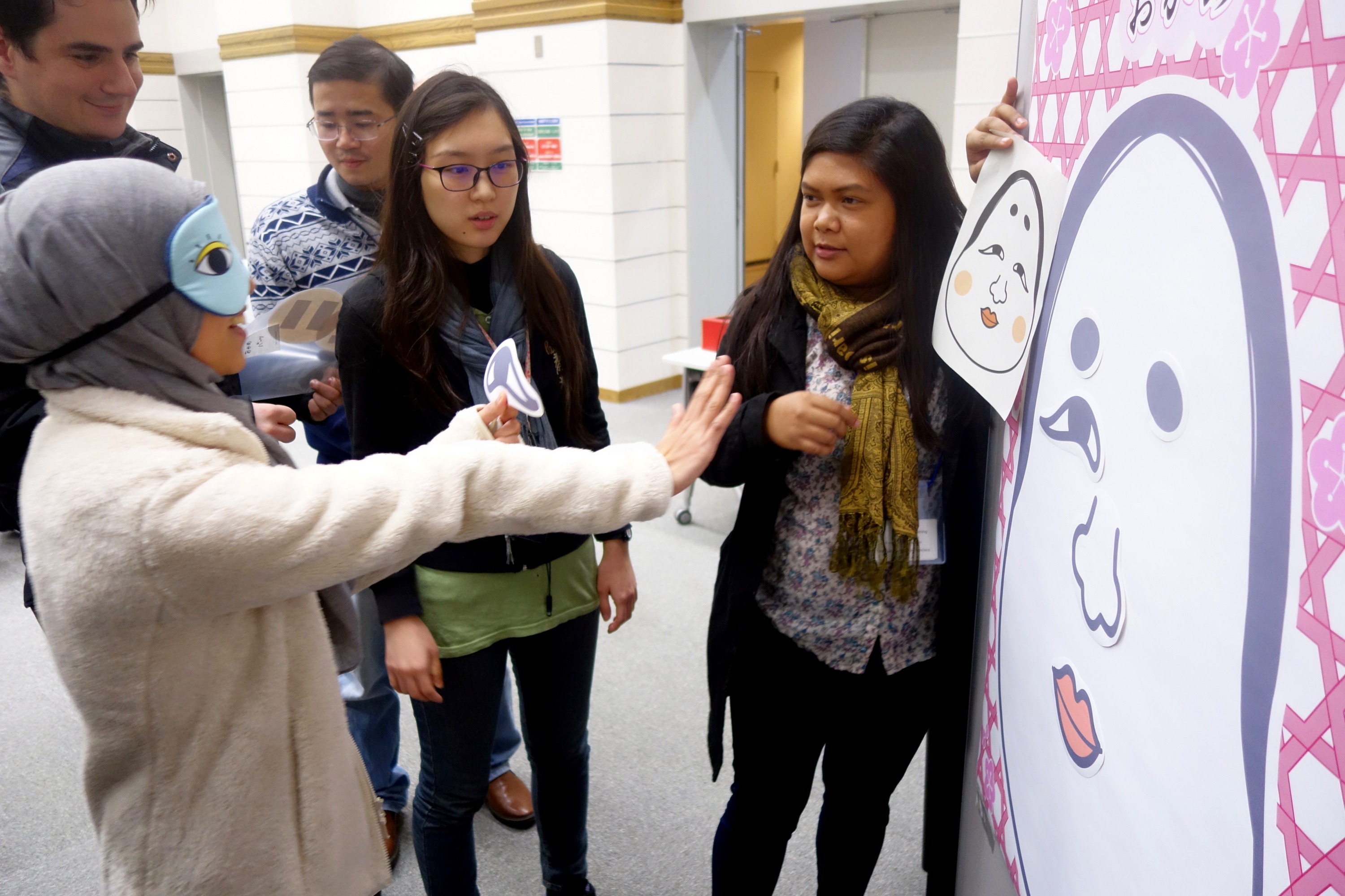 A student is instructed to pin an eye on a helpless face at the NAIST Tea Time.